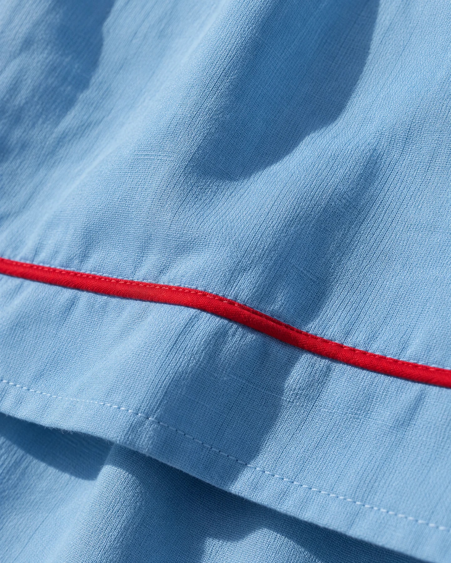 Pantalón Do Santos en azul con bordado rojo, en macro, la textura del material
