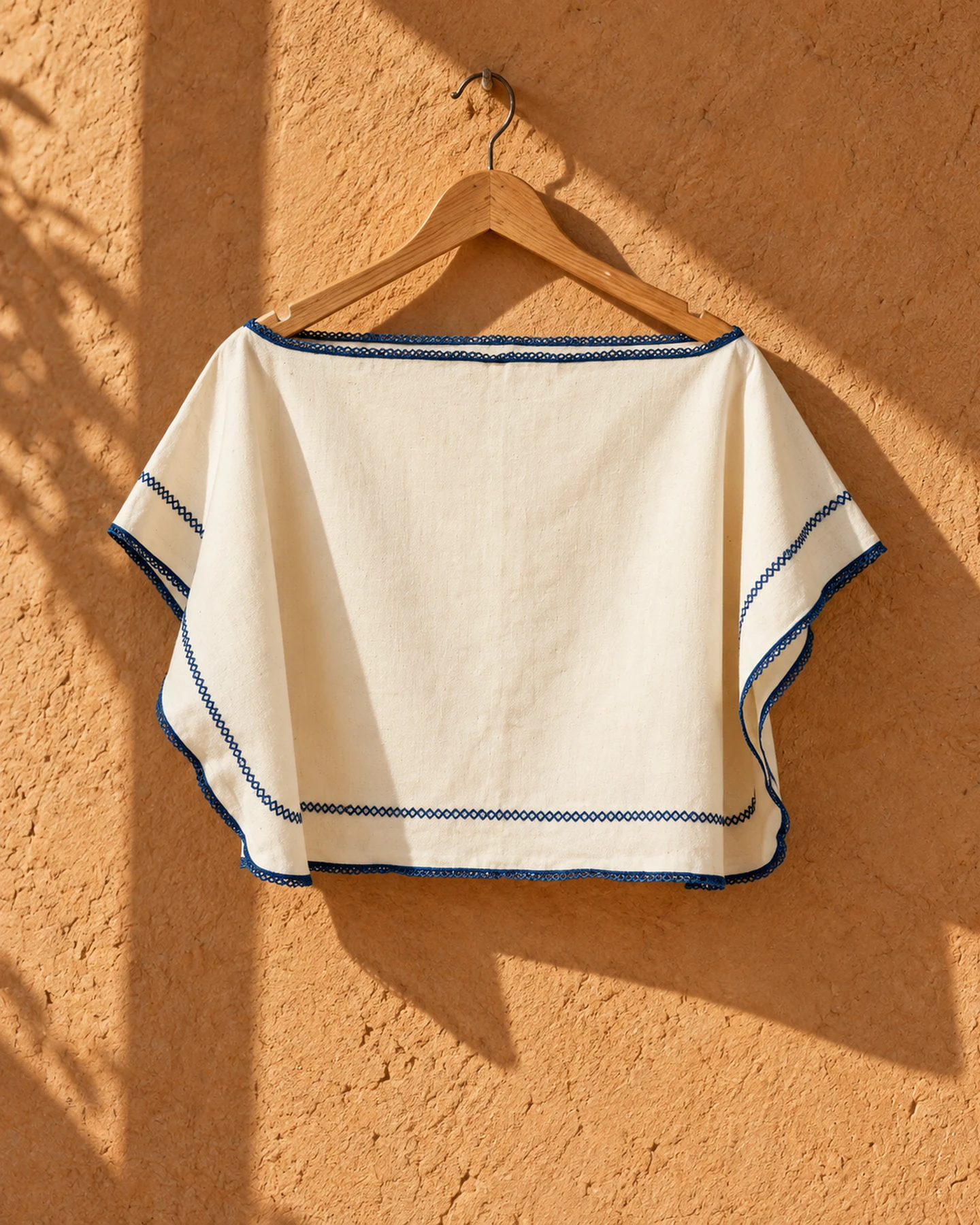 Poncho Cannes en crudo con bordado azul, de frente, sola