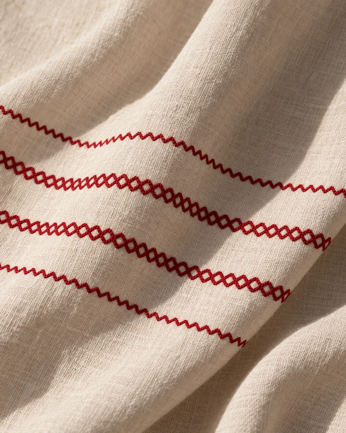 Poncho Marbella de lino en crudo con bordado rojo, en macro, la textura del material
